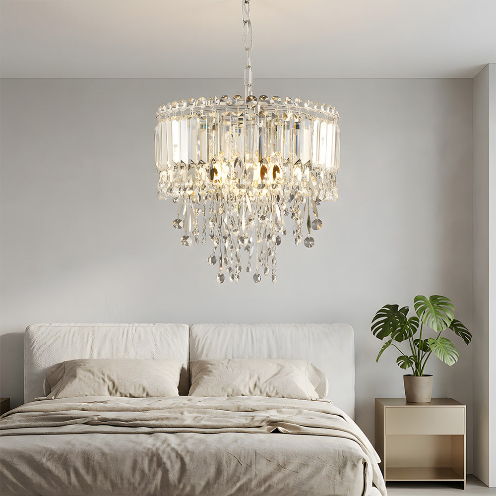 Chandelier hanging above a bed in a bedroom with a plant on a nightstand.