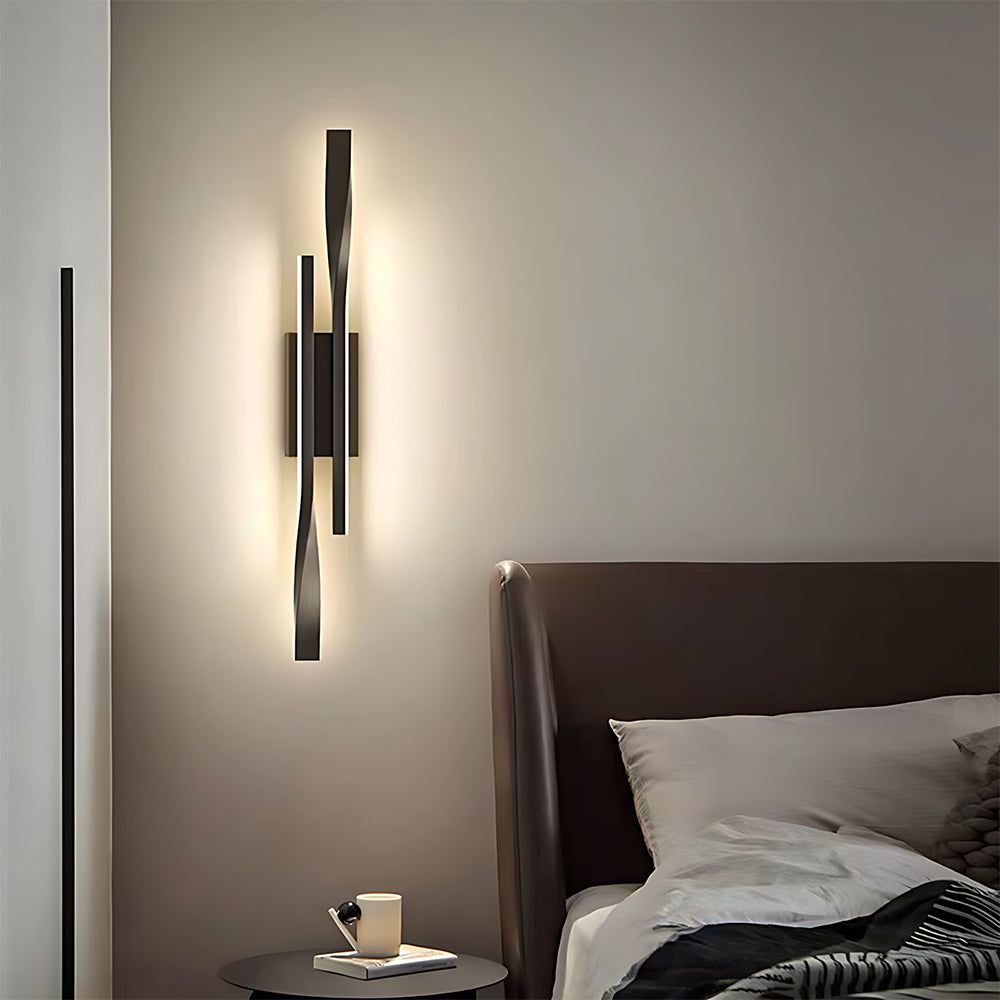 Modern wall sconce on a neutral wall above a bed with a side table.