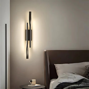 Modern wall sconce on a neutral wall above a bed with a side table.