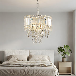 Chandelier hanging above a bed in a bedroom with a plant on a nightstand.