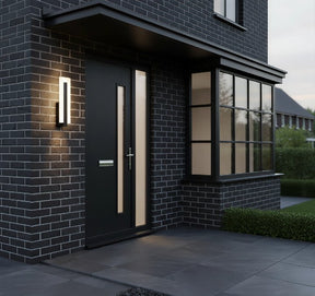 Modern black door on a brick house with exterior lighting